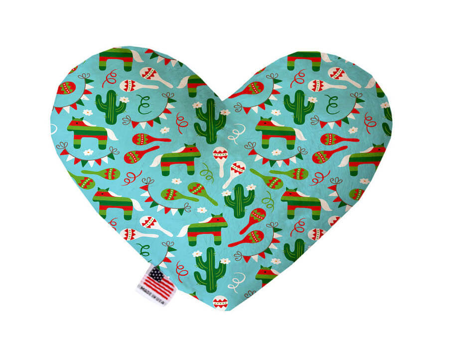 Heart shaped squeaker dog toy. Turquoise background with red maracas, green cacti and donkey piñatas printed throughout. Made in USA label on bottom trim.