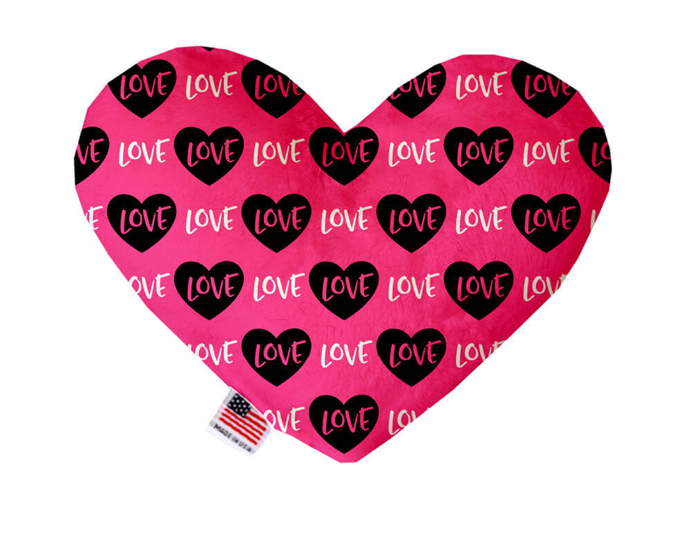 Heart shaped squeaker dog toy. Pink background with black hearts and "Love" text printed throughout. Made in USA label on bottom trim.