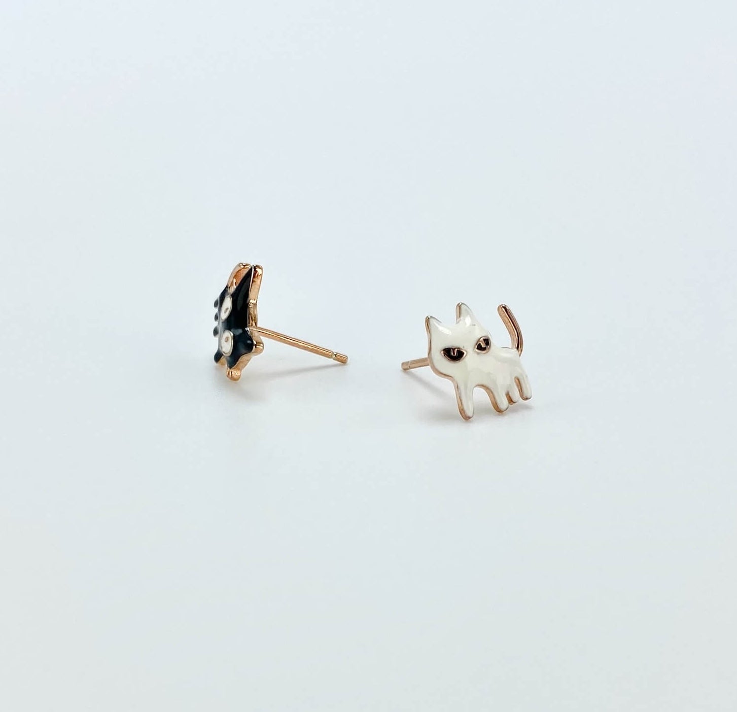 Intentionally mismatched cat stud earrings (one is black and one is white).