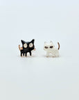 Intentionally mismatched cat stud earrings (one is black and one is white).