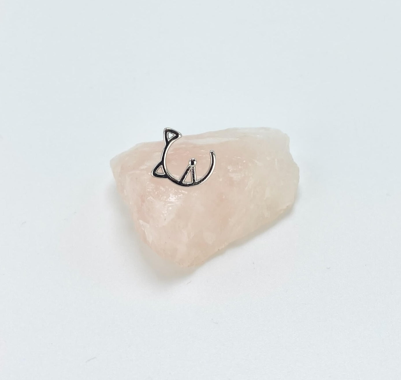 Geometric half cat face sterling silver stud earring sitting on rose quartz stone.