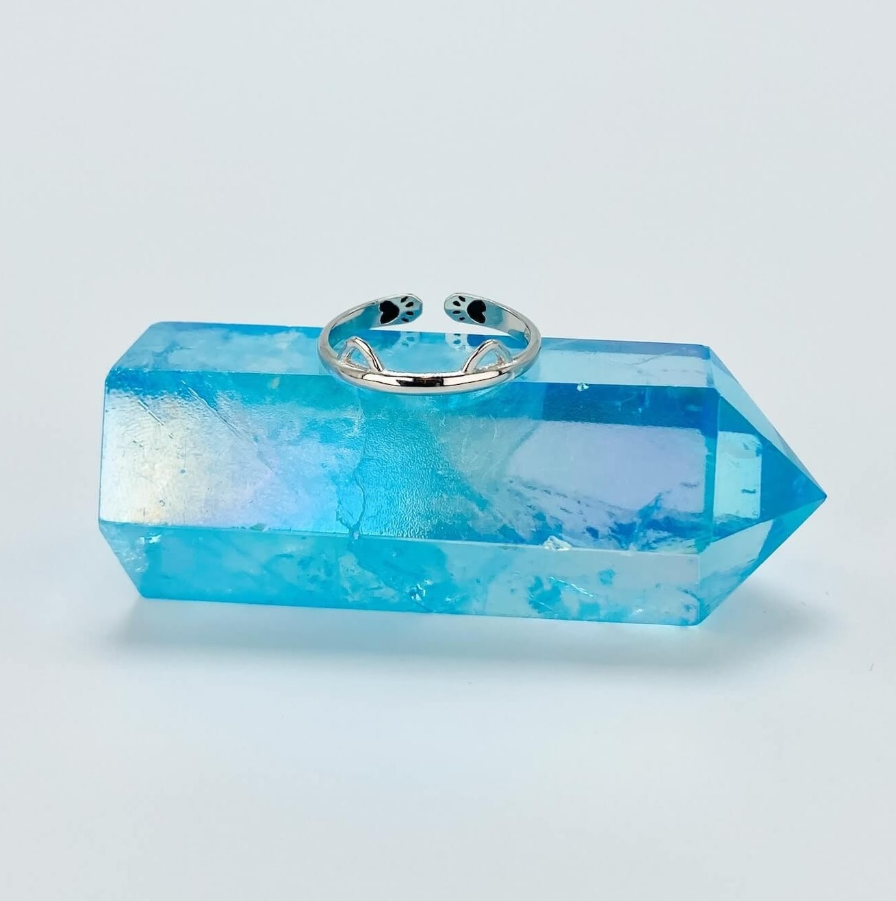 Sterling silver band ring with cat ears sitting on blue crystal stand.