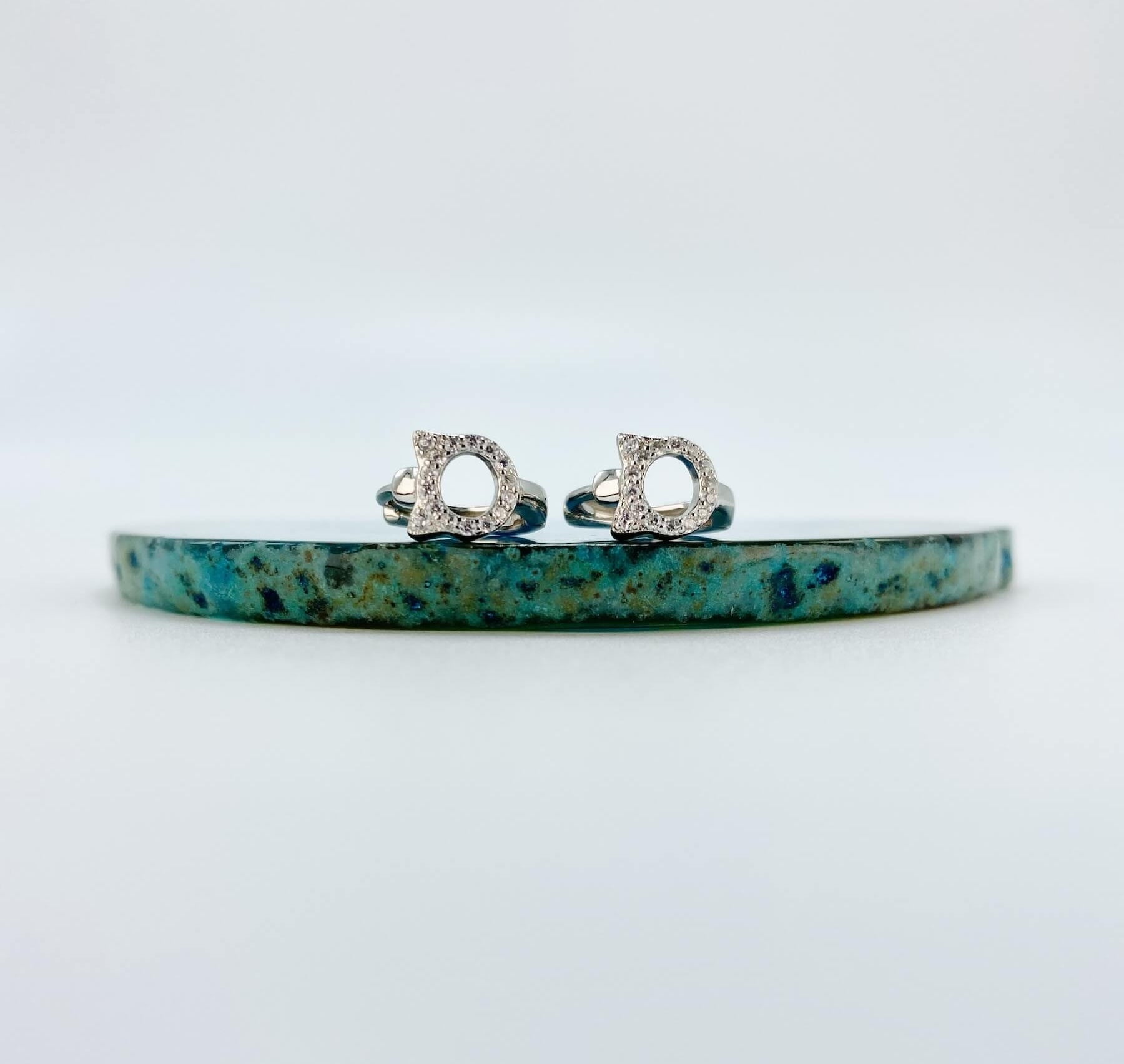 Sterling silver cubic zirconia cat huggie earrings.