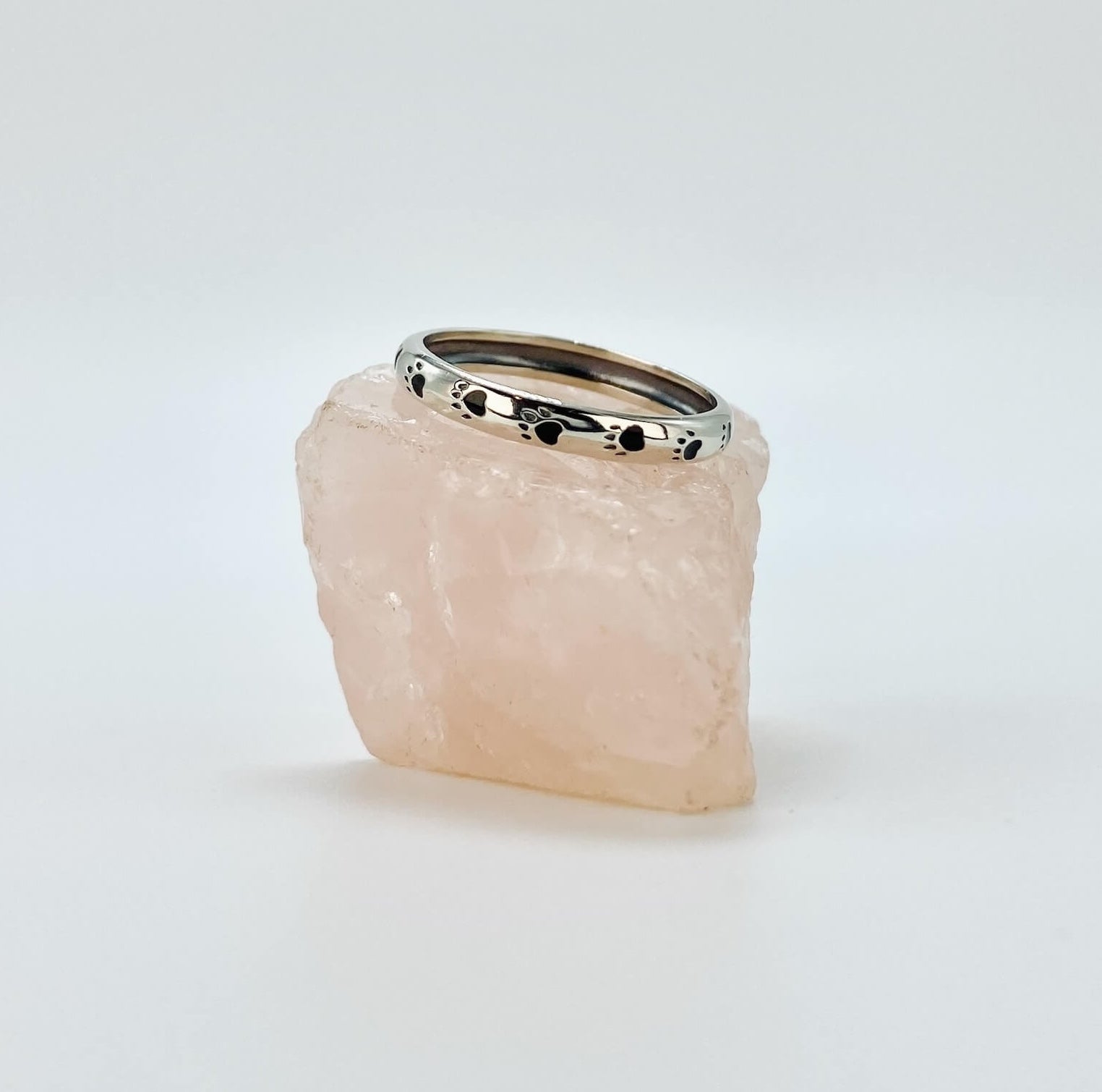 Sterling silver band ring with black enameled paw prints.