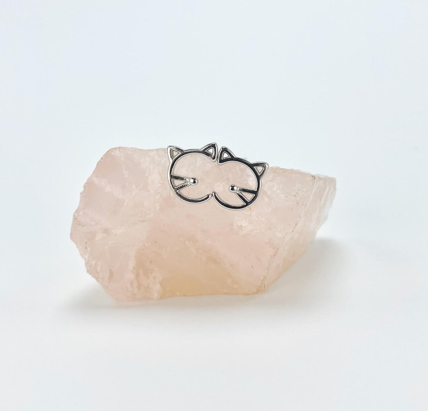 Geometric half cat face sterling silver stud earrings sitting on rose quartz stone.