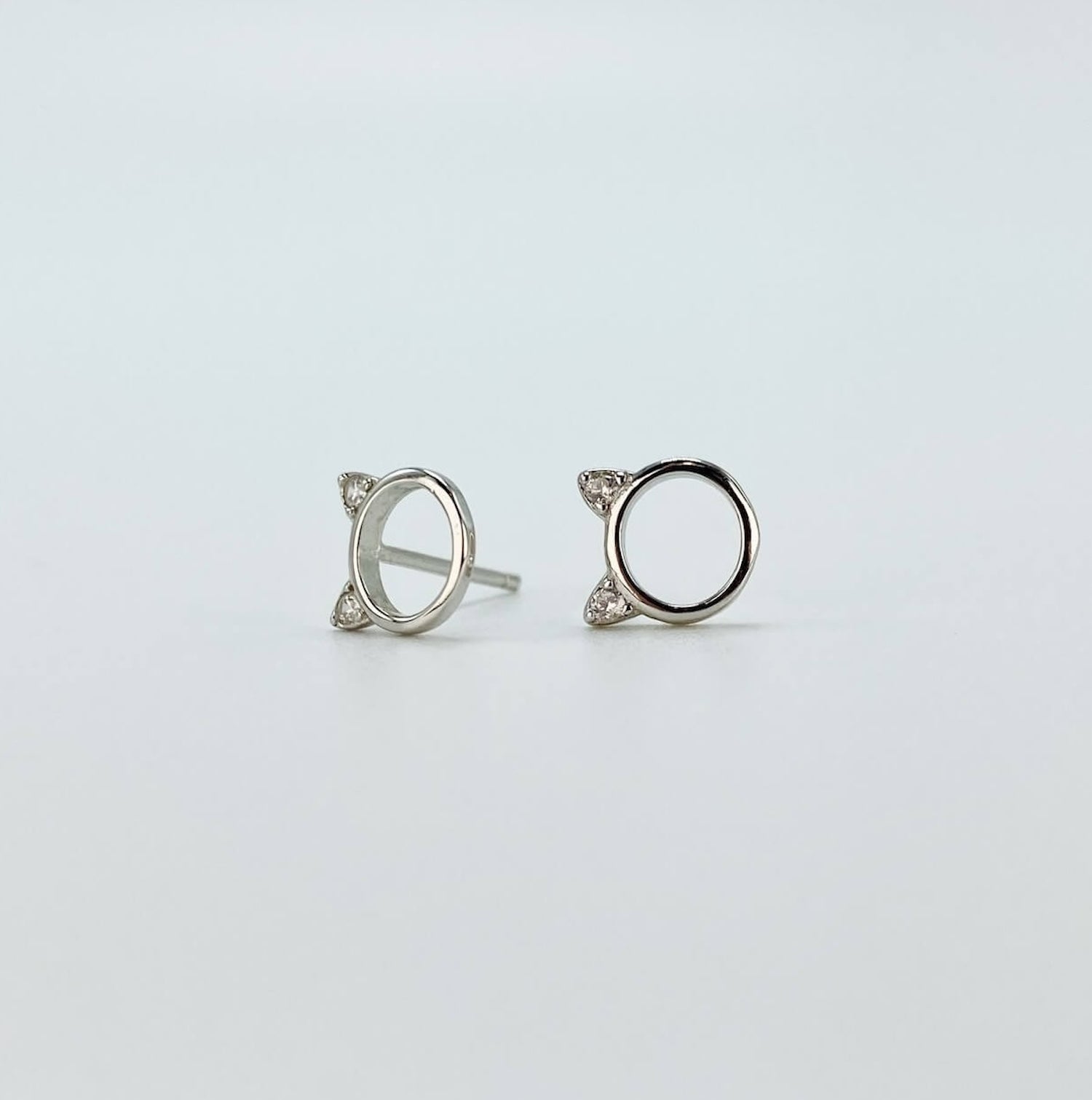 Sterling silver minimalist cat head "o" stud earrings with cubic zirconia gems in silver.