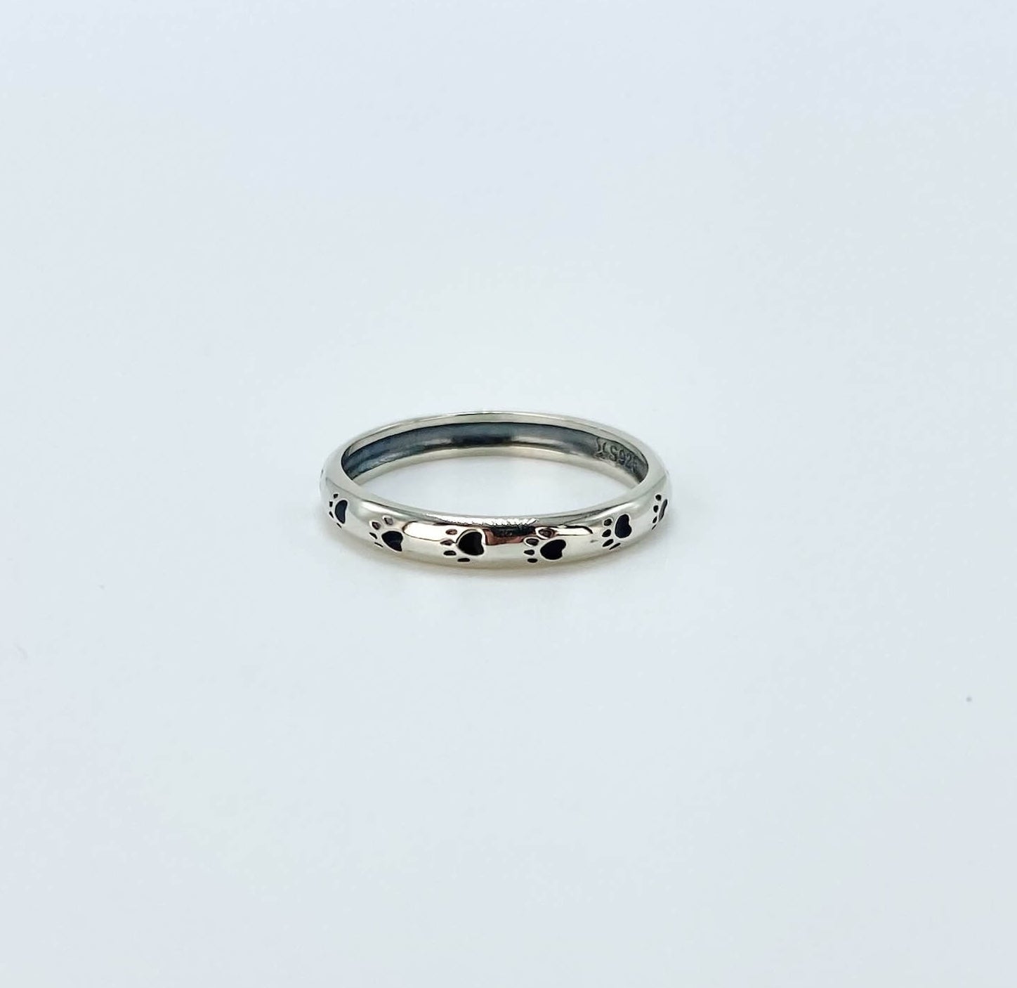 Sterling silver band ring with black enameled paw prints.
