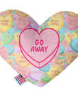 Heart shaped squeaker dog toy. Multicolored Valentine's Day candy heart background with 'Go Away' heart in the center. Made in USA label on bottom trim.