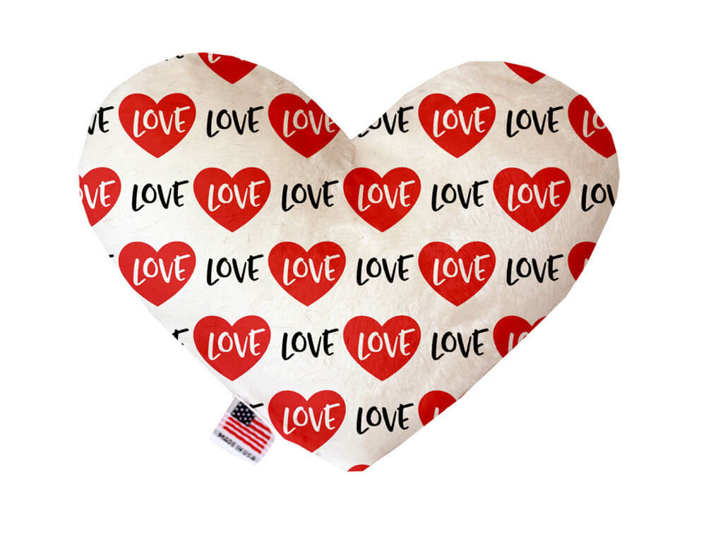 Heart shaped squeaker dog toy. White background with red hearts and "Love" text printed throughout. Made in USA label on bottom trim.