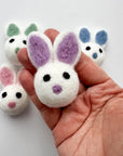 An Easter bunny felted wool cat toy being held in someone's hand to show size and scale.