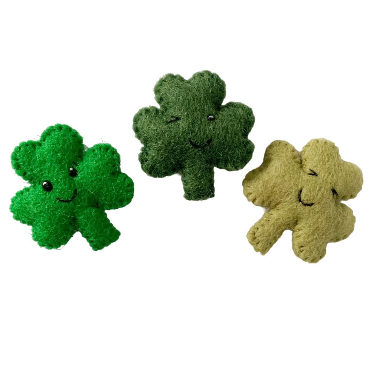 Three anthropomorphic shamrocks in different shades of green, made of wool.