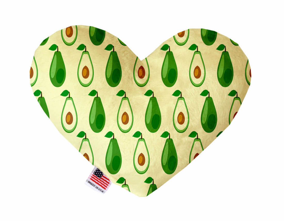 Heart shaped squeaker dog toy. Yellow background with a repeating avocado print. Made in USA label on bottom trim.