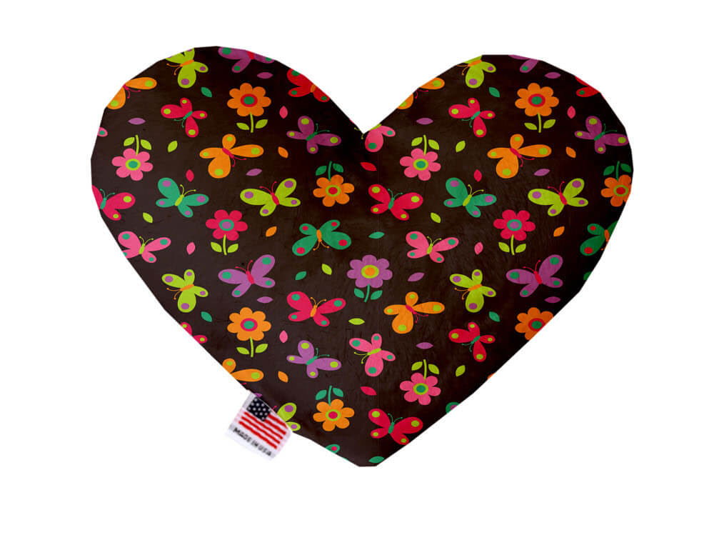 Heart shaped squeaker dog toy. Brown background with colorful butterflies and flowers printed throughout. Made in USA label on bottom trim.