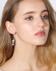 Cat and fishbone rhinestone drop earrings worn by model.