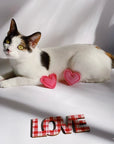 Cat posing with two felted catnip heart cat toys.