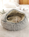Cat sleeping in a gray plush nesting cave pet bed.