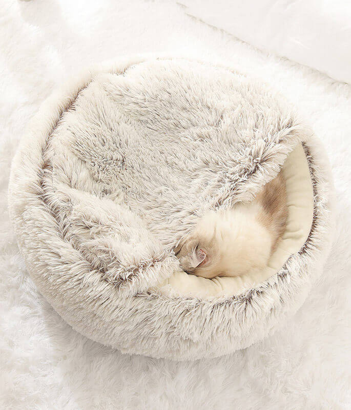 Cat cozied and snuggled up into its plush nesting cave bed.