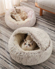 Two cats sitting in their plush nesting cave beds. One cat is inside the cave, and the other cat is sitting on top of it.