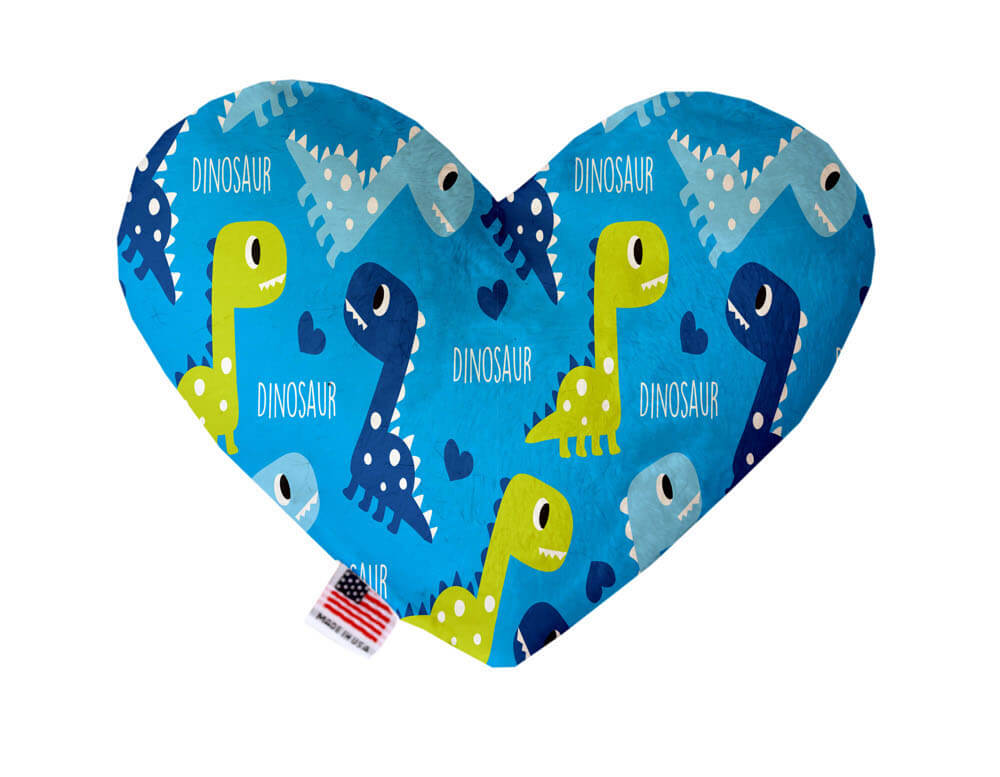 Heart shaped squeaker dog toy. Blue background with baby blue, navy blue and lime green dinosaurs printed throughout. Made in USA label on bottom trim.