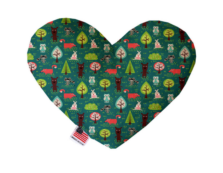 Heart shaped squeaker dog toy. Green background with bears, foxes, rabbits, raccoons and owls, as well as forest flora and fauna printed throughout. Made in USA label on bottom trim.