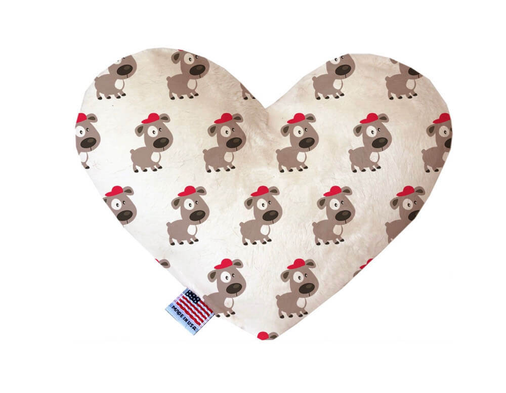 Heart shaped squeaker dog toy. White background with brown dogs wearing red hats printed throughout. Made in USA label on bottom trim.