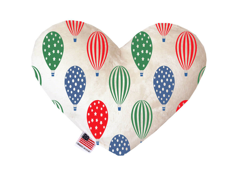 Heart shaped squeaker dog toy. White background with red, blue and green hot air balloons printed throughout. Made in USA label on bottom trim.