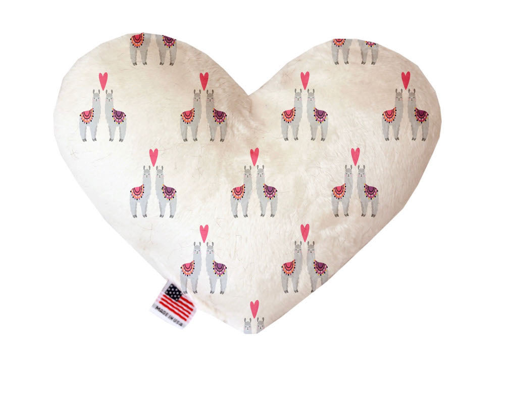 Heart shaped squeaker dog toy. White background with llamas and hearts printed throughout. Made in USA label on bottom trim.