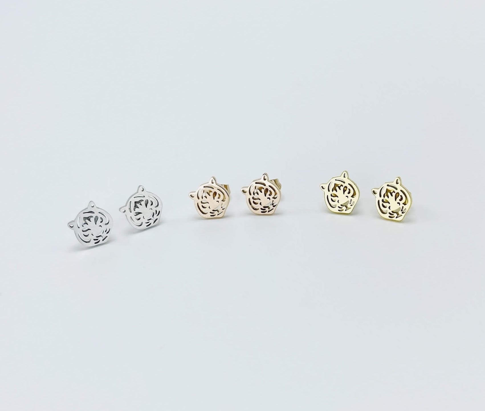 Metallic tiger stud earrings made from stainless steel. Colors shown: silver, rose gold and yellow gold.