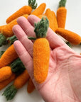 Someone holding an orange carrot felted wool cat toy in their hand to show size and scale.