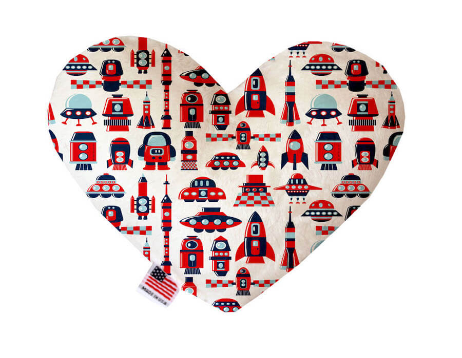 Heart shaped squeaker dog toy. White background with red rocket ships, UFOs and alien spacecrafts printed throughout. Made in USA label on bottom trim.