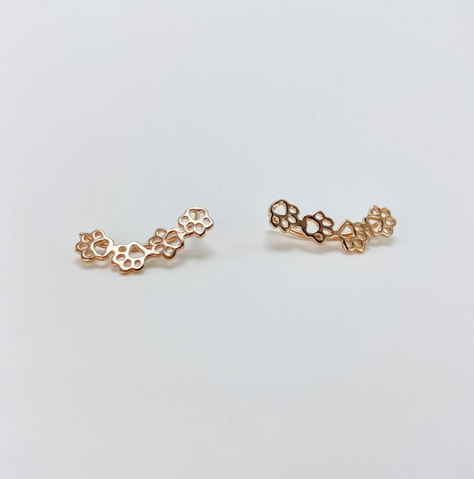 Sterling silver paw print climber earrings in rose gold.