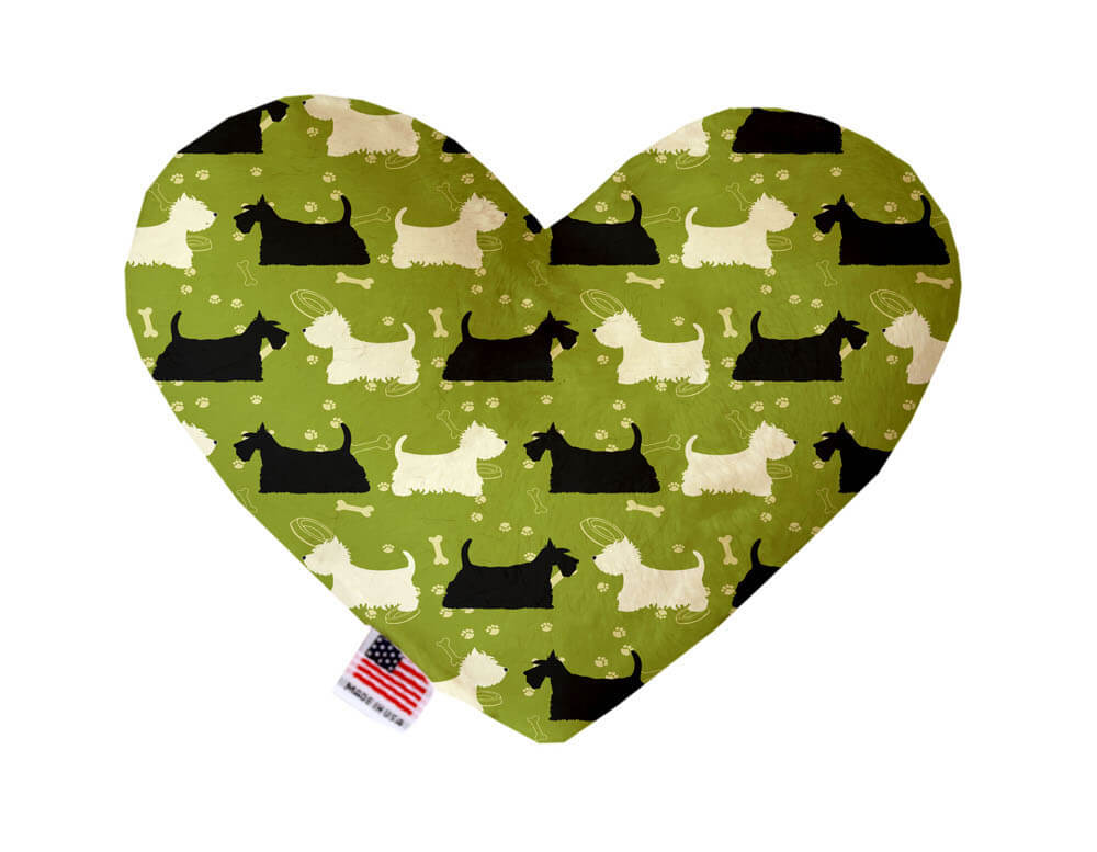 Heart shaped squeaker dog toy. Green background with white and black Scottie and Westie silhouettes printed throughout. Made in USA label on bottom trim.