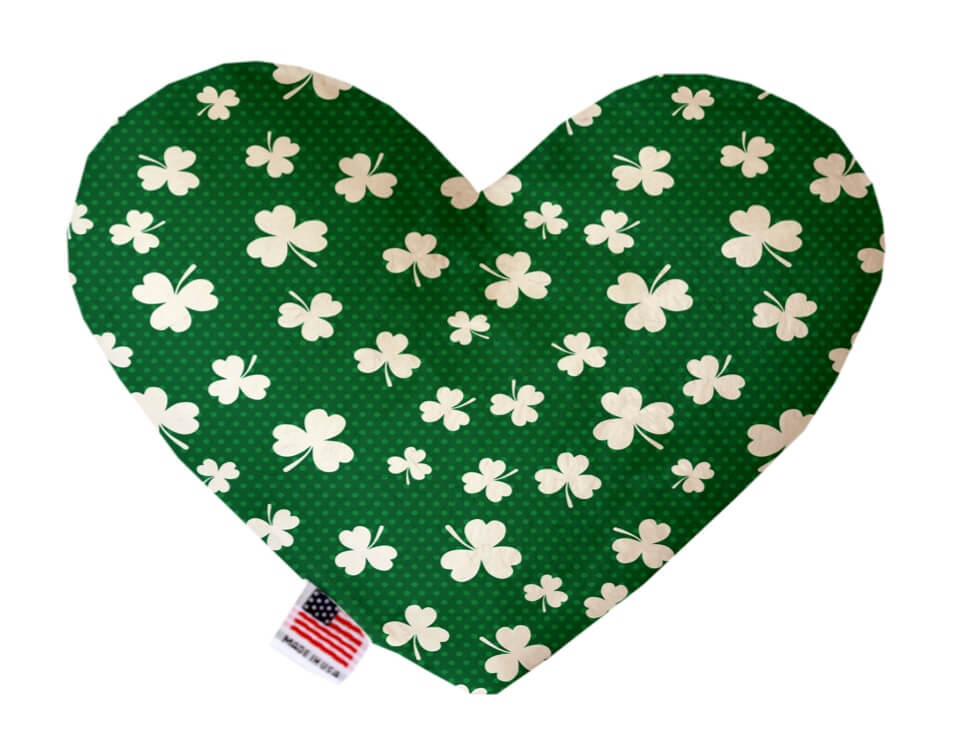St. Patrick's Day themed heart shaped squeaker dog toy. Green background with white shamrocks printed throughout. Made in USA label on bottom trim.