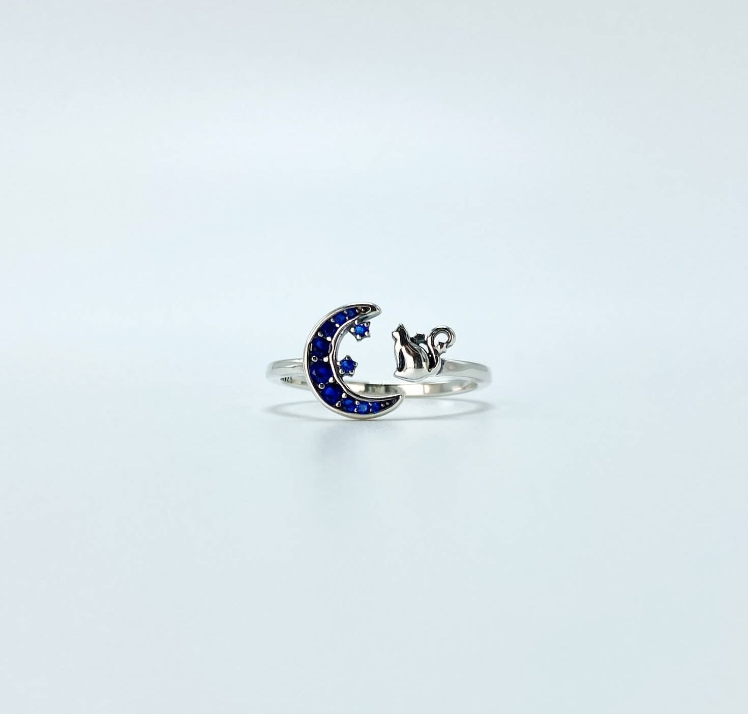 Sterling silver cat and moon ring with blue cubic zirconia gemstones in a pave setting.