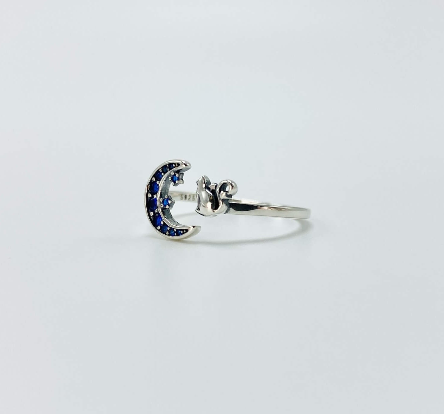 Sterling silver cat and moon ring with blue cubic zirconia gemstones in a pave setting.
