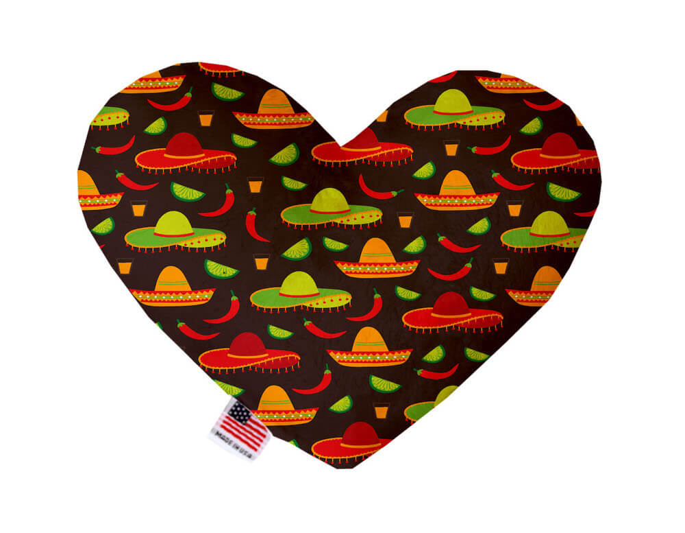 Heart shaped squeaker dog toy. Brown background with red, orange and green sombreros, tequila shots, limes and chili peppers printed throughout. Made in USA label on bottom trim.