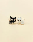 Intentionally mismatched cat stud earrings (one is black and one is white).