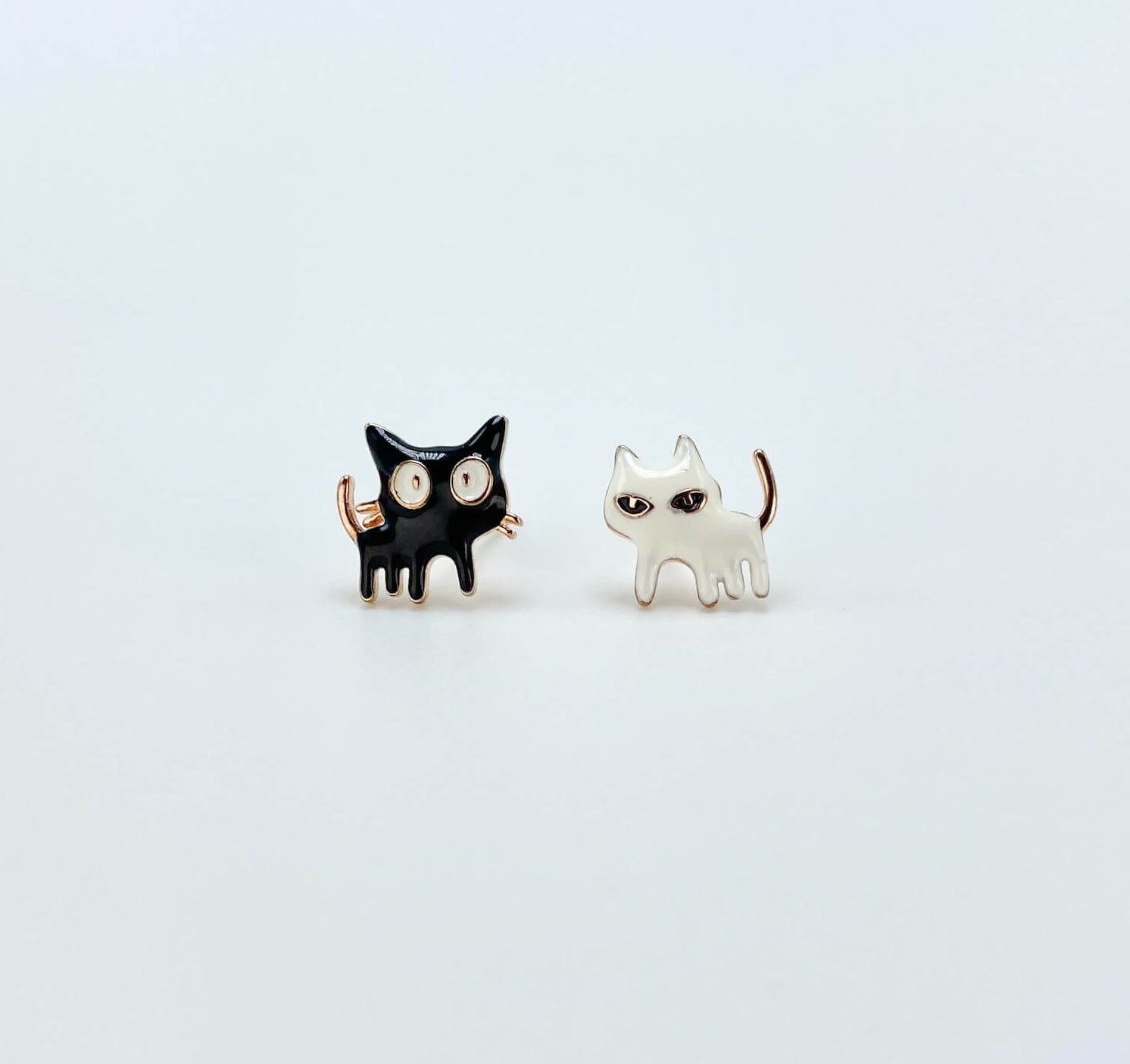 Intentionally mismatched cat stud earrings (one is black and one is white).