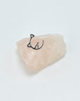 Geometric half cat face sterling silver stud earring sitting on rose quartz stone.