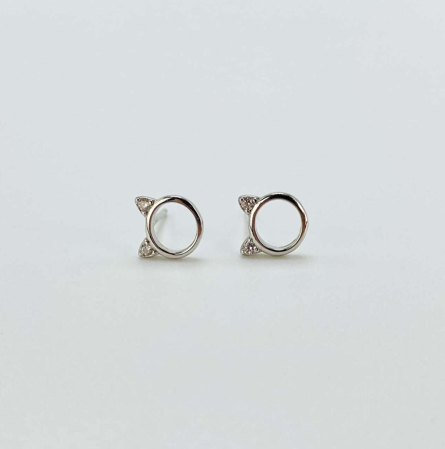 Sterling silver minimalist cat head "o" stud earrings with cubic zirconia gems in rose gold and silver.