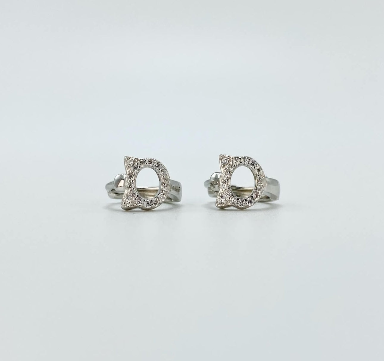 Sterling silver cubic zirconia cat huggie earrings.