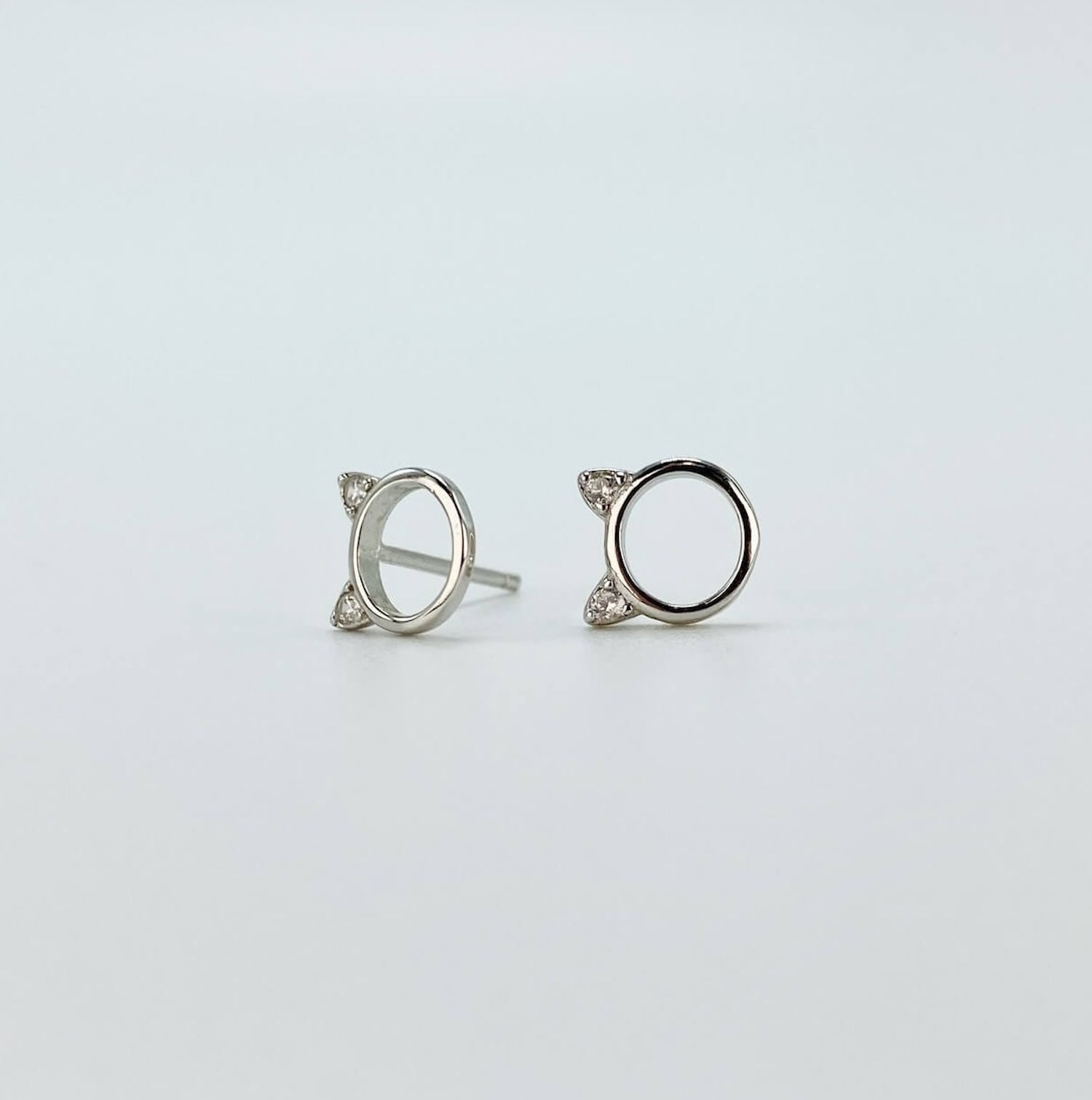 Sterling silver minimalist cat head &quot;o&quot; stud earrings with cubic zirconia gems in silver.