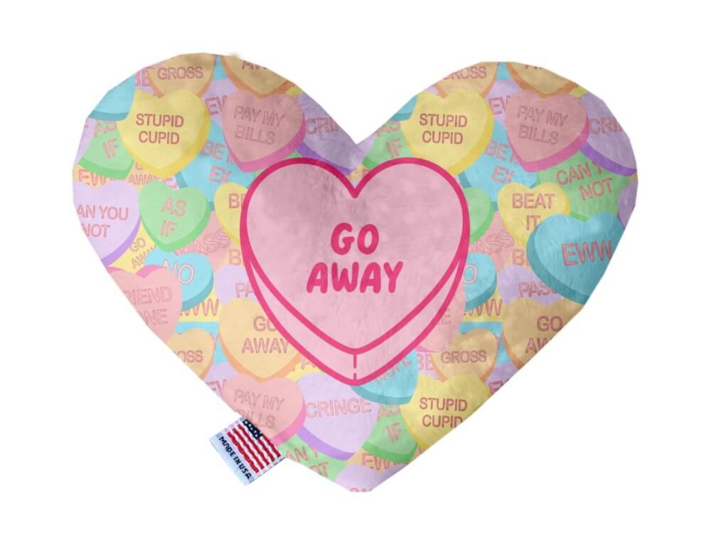 Heart shaped squeaker dog toy. Multicolored Valentine's Day candy heart background with 'Go Away' heart in the center. Made in USA label on bottom trim.