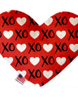 Heart shaped squeaker dog toy. Red background with white hearts and black "XO" text printed throughout. Made in USA label on bottom trim.