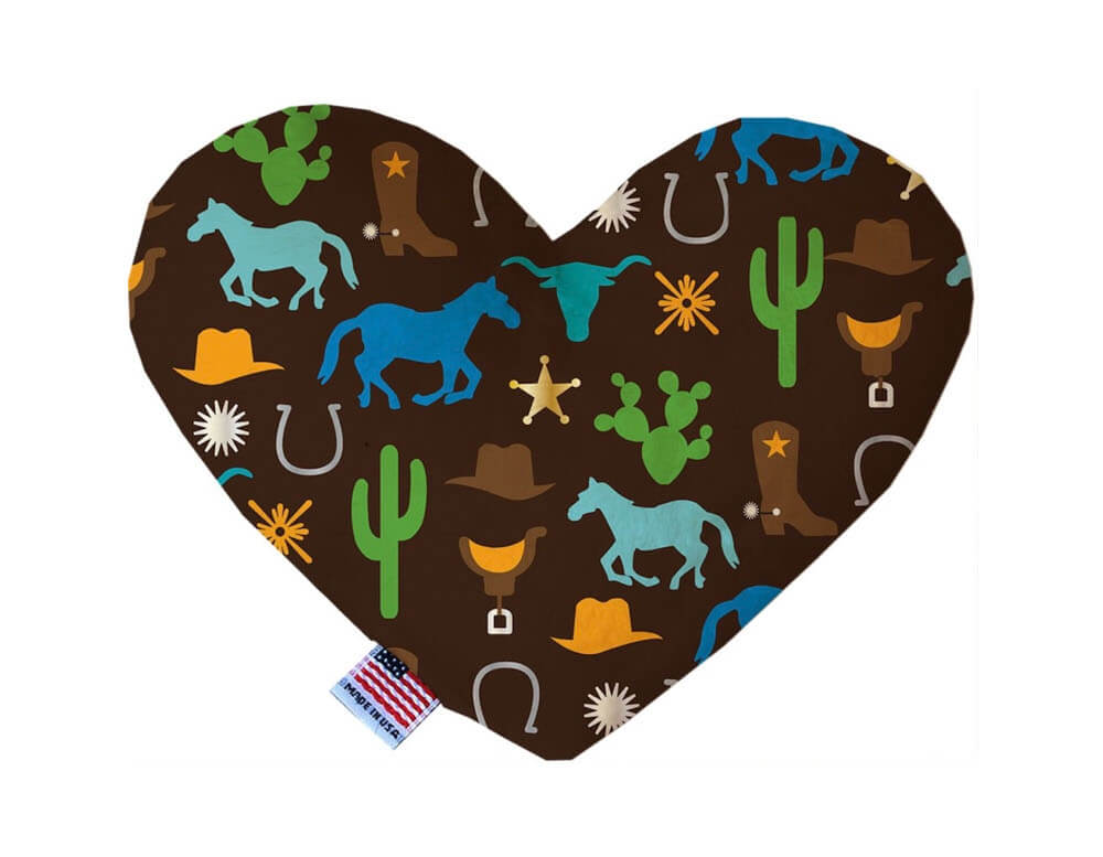 Heart shaped squeaker dog toy. Brown background with cowboy hats & boots, horses, horse saddles & shoes, bulls, and cacti printed throughout. Made in USA label on bottom trim.