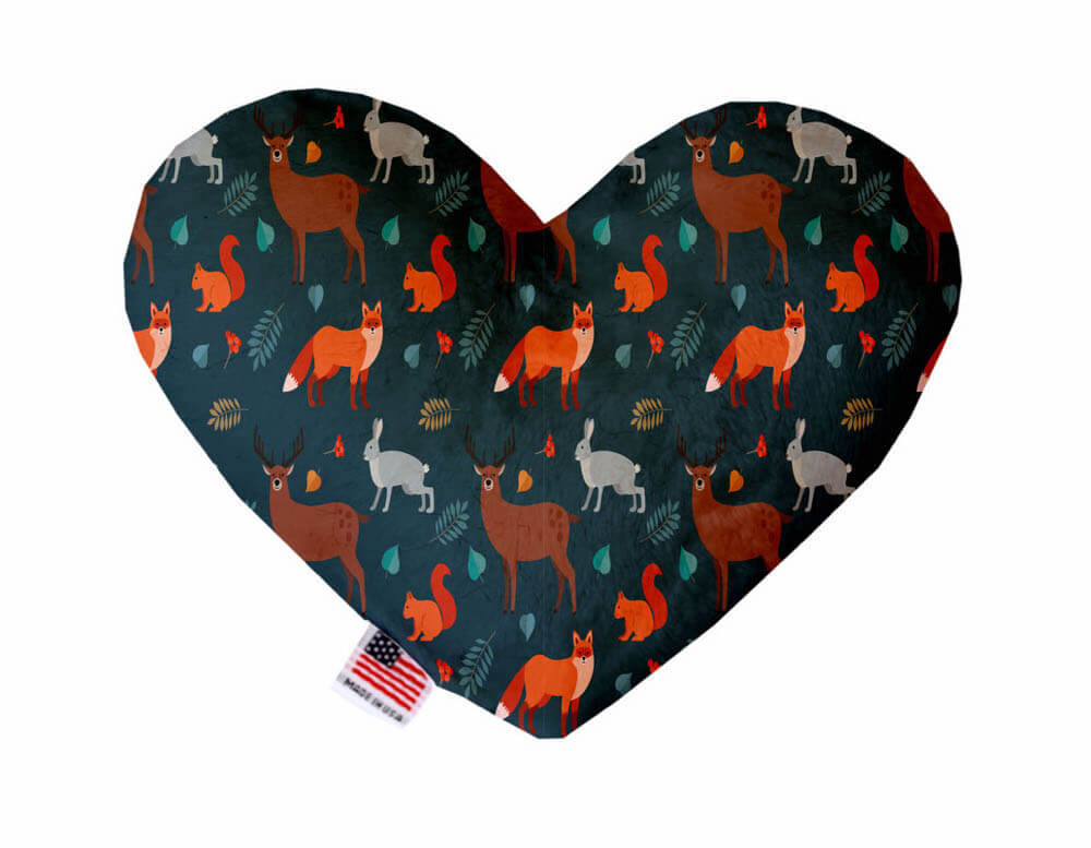 Heart shaped squeaker dog toy. Blue background with deer, foxes, rabbits, squirrels and fall leaves printed throughout. Made in USA label on bottom trim.
