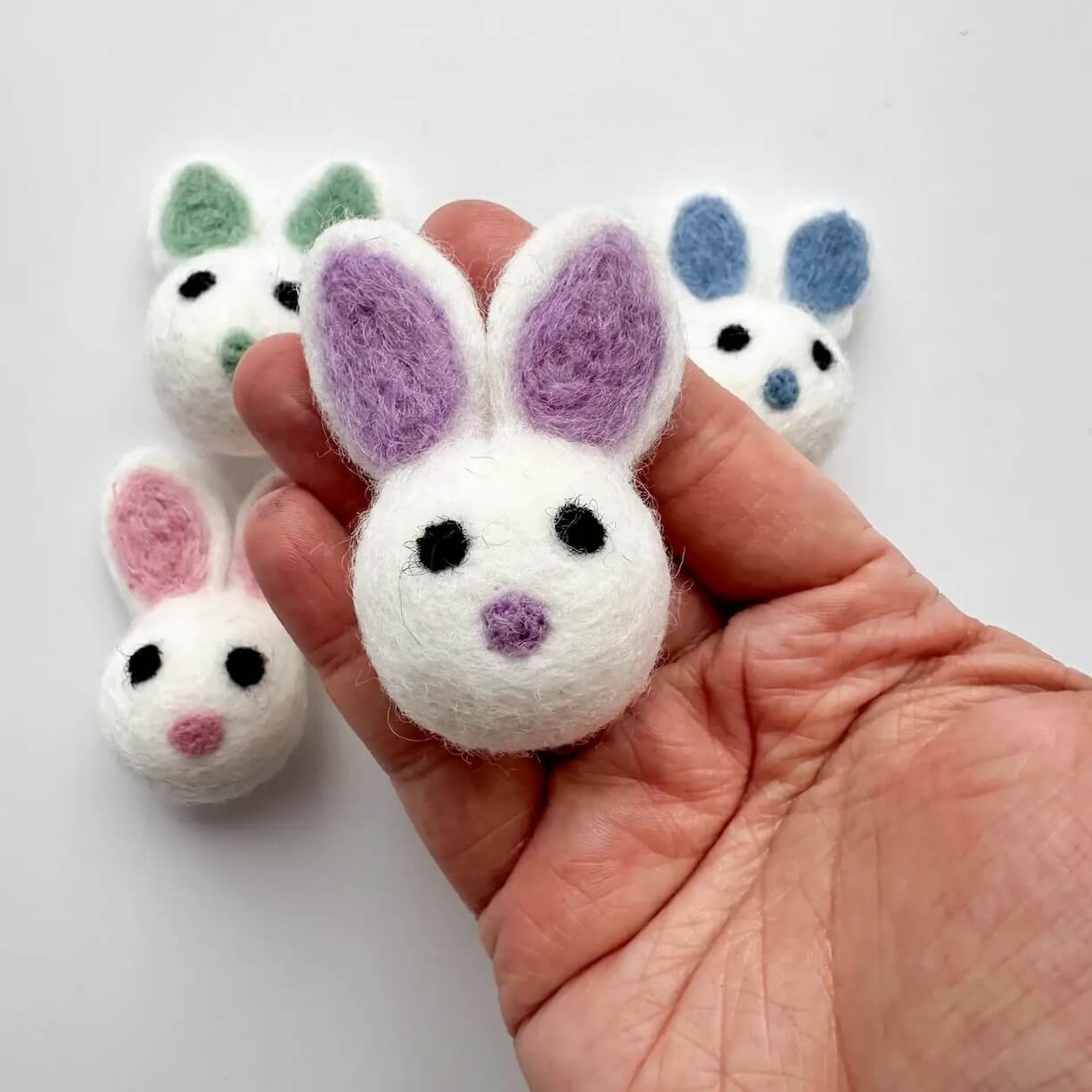 An Easter bunny felted wool cat toy being held in someone's hand to show size and scale.
