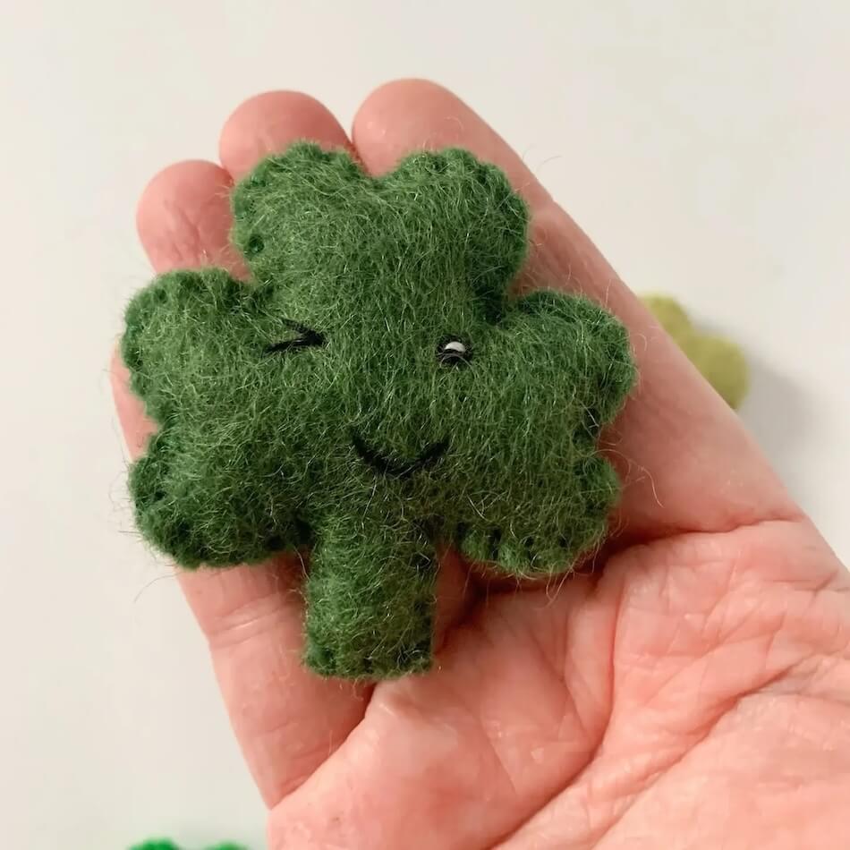 Green wool shamrock held in a person&#39;s hand to show scale.