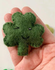 Green wool shamrock held in a person's hand to show scale.